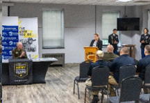 MG Schindler looks on as Dr. Harry provides remarks