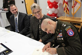 LTC Ramon Ramos signs the ceremonial Army PaYS certificate as Stacy Winsett and Jim Wojciechowski look on, marking the official launch of the partnership between RATP Dev USA and the U.S. Army.