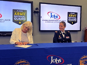 COL Johnson looks on as Commissioner Catherine Munoz signs the PaYS ceremonial Memorandum of Agreement.